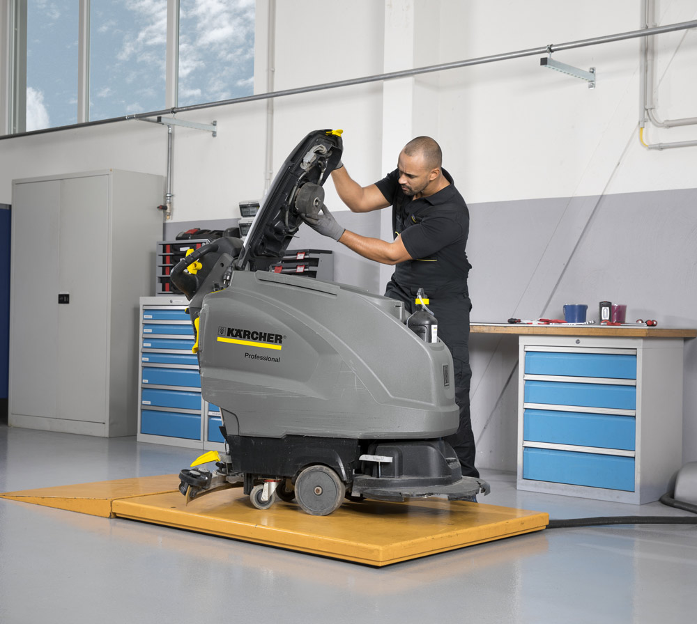 Servicetechniker wartet eine Kärcher Scheuersaugmaschine in der Werkstatt und prüft das geöffnete Aggregat.