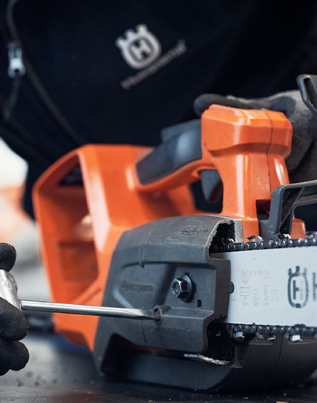 Reparatur einer Motorsäge bei Werkzeug Schultze – Fachkraft justiert die Kette im Rahmen des Reparatur- und Wartungsservices.