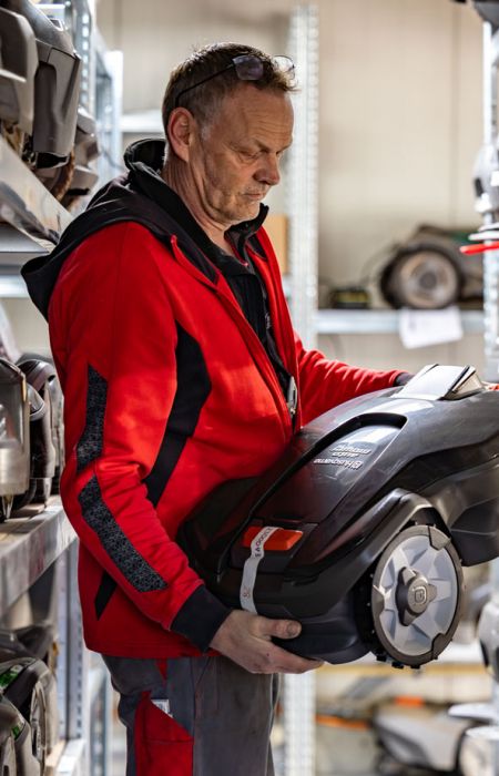 Mitarbeiter von Werkzeug Schultze prüft einen Mähroboter im Lager – Service, Wartung und fachgerechte Vorbereitung der Geräte.