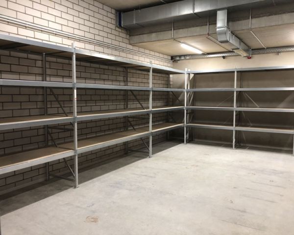 Metallregalanlage in Lagerraum mit Betonboden und Ziegelwand – stabile Fachböden für effiziente Lagerorganisation.