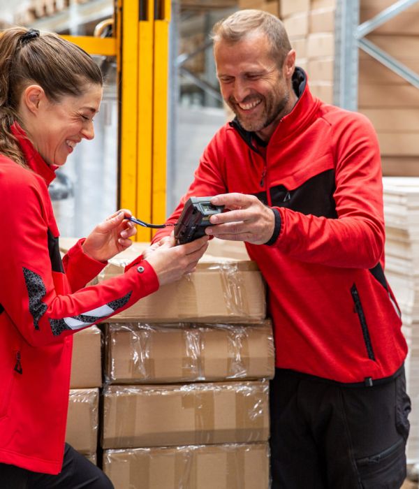 Zwei Mitarbeiter in Arbeitskleidung im Lager – funktionale Berufsbekleidung für Logistik, Industrie und Handwerk im Einsatz.