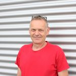 Porträt eines Werkstattmonteurs von Werkzeug Schultze vor dem Firmengebäude – persönlicher Ansprechpartner für Rasenroboter.